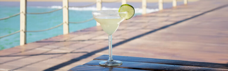 copa margarita con sal en el borde y limón verde sobre mesa de madera
