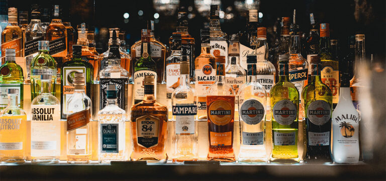 estante de bar iluminado con botellas de tequila gin bourbon ron y mezcal