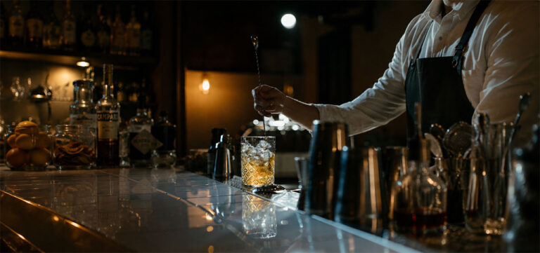 bartender revolviendo coctel en bar oscuro con iluminación tenue