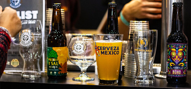 stand de expo cerveza méxico con botellas de cerveza artesanal y vaso oficial